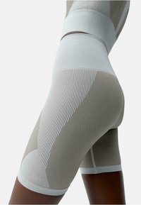 High-waisted shorts van een beige en witte ribbelstof. Beschikt over textuurpatronen en een strakke pasvorm. Korte lengte met contrasterende banden.