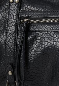 Sac en cuir noir texturé doté d'un compartiment zippé avec quincaillerie en argent et d'une languette en cuir décorative.