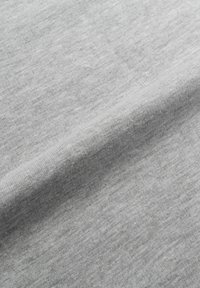 Tessuto grigio chiaro con una texture morbida e un sottile motivo mélange, delicatamente drappeggiato per mostrare pieghe e contorni naturali.