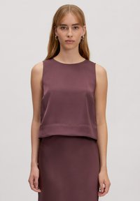 Mouwloos topje in een diepe mauve tint, met een gladde satijnen textuur en een iets verkorte ontwerp. Eenvoudige halslijn met minimale accenten.