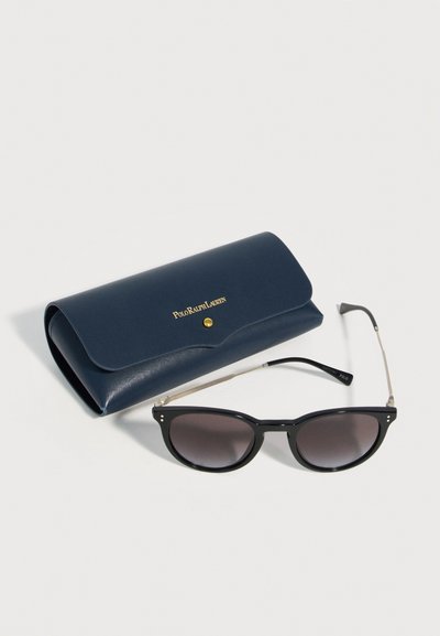 Μαύρα γυαλιά ηλίου με πλαίσιο και φακούς με διαβάθμιση δίπλα σε μία ναυτικό μπλε θήκη Polo Ralph Lauren με χρυσό κουμπί και λογότυπο.