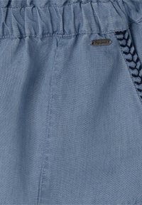 Pantalones cortos de tela azul claro con cintura fruncida, que presentan un pequeño logo metálico y un ribete decorativo trenzado en color navy a lo largo del costado.