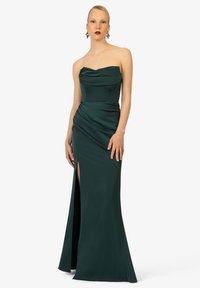 Trägerloses Abendkleid aus tiefgrünem Stoff, mit drapierten Details, einem Oberschenkel hohen Schlitz und einer taillierten Silhouette.