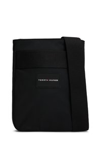 Fekete nylon keresztpántos táska texturált pánttal. Téglalap alakú, és a elején logóval rendelkezik. Egyszerű, funkcionális dizájn.