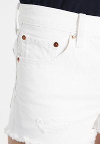 Witte denim shorts met een rafelige zoom, verweerde accenten en koperen hardware, en een klassiek ontwerp met vijf zakken.