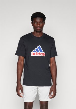 Must musta särk musta, millel on rindkeres suur punane ja sinine Adidas logo. Lühikesed varrukad, ringkaelus, tavaline lõige.