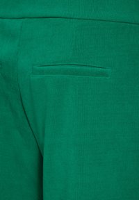 Grön ribbad tyg med en slät textur, med en liten, rektangulär ficka integrerad i designen.