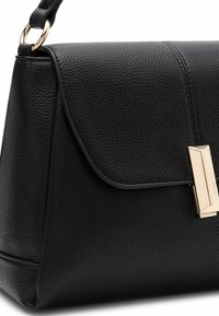 Schwarze Lederhandtasche mit strukturiertem Finish, Klappenverschluss und Akzenten in Goldton. Winklige Form mit sorgfältig genähten Nähten.