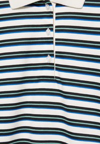 Gros plan d'un polo blanc avec des rayures horizontales noires, bleues et vertes et trois boutons blancs sous le col.