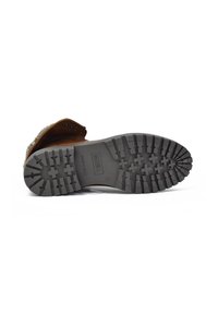 Bota de cuero marrón con una suela de goma texturizada y tacos profundos para un mejor agarre. Interior forrado con un material suave para mayor comodidad.