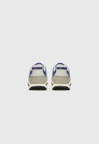 Blå och grå sneakers med en texturerad mockabaksida, platta snören och en beige sula. Har en lila logotyp på hälen.