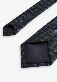 Navy blue tie with a herringbone pattern, featuring textured accents and a solid darker interior. The ends are pointed and well-constructed.