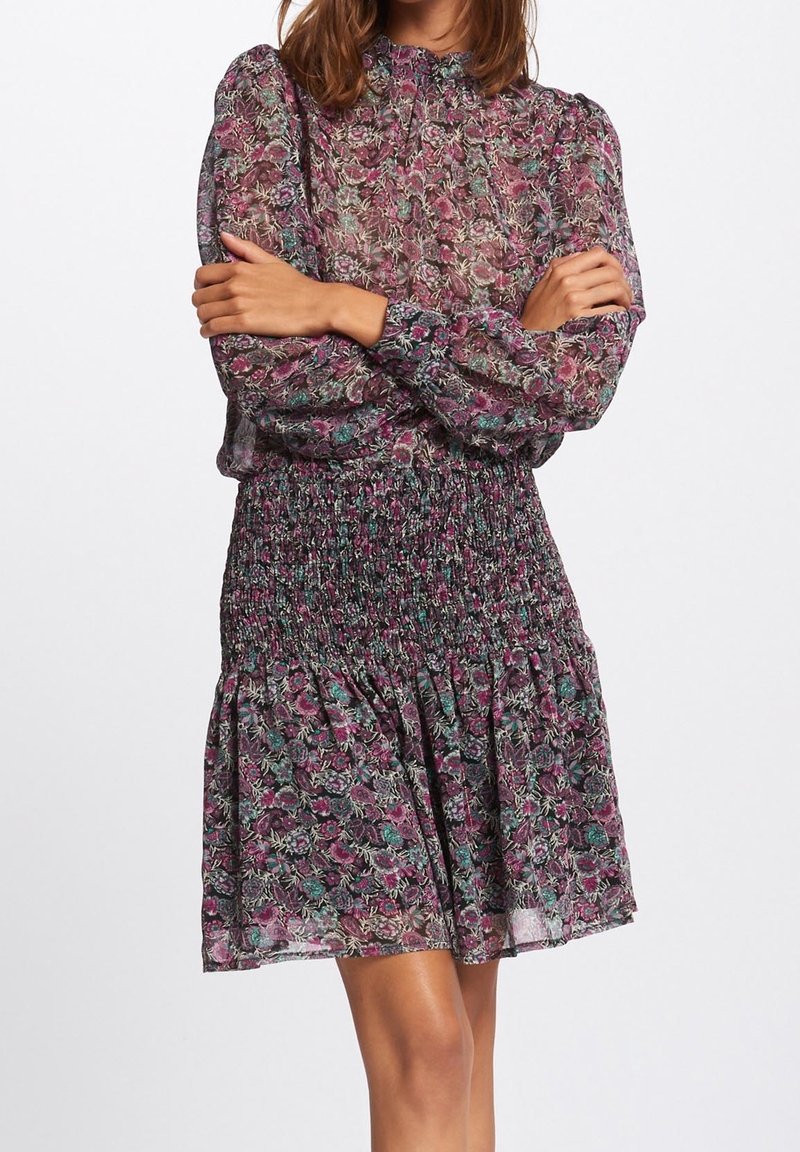 Kortærmet, blomstermønstret kjole i let og gennemsigtigt materiale. Har smocket talje og plisseret nederdel, hovedsageligt lilla med grønne accenter.