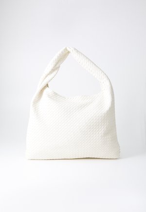 Weißer geflochtener Handtasche mit einem gebogenen, kurzen Griff. Weiche Textur und eine lässige Form, die ein filigranes Korbmuster präsentiert.