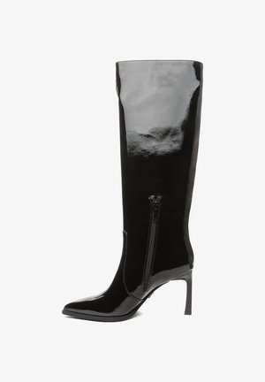 Botas negras de charol hasta la rodilla con punta afilada y tacón de aguja delgado. Cuentan con una cremallera lateral para facilitar su uso.