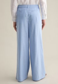 Pantalones de pierna ancha azul claro con rayas verticales, hechos de una tela suave; cuentan con dos bolsillos traseros y una cinturilla ajustada.