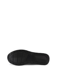 Suola di sneaker nera in gomma con superficie testurizzata, caratterizzata da profonde scanalature e nervature per la trazione, e un design piatto e largo.