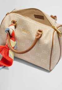 Borsa a tracolla beige con texture, motivo logo chiaro, manici in pelle marrone e una sciarpa colorata legata a un manico. Chiusura con zip in oro.