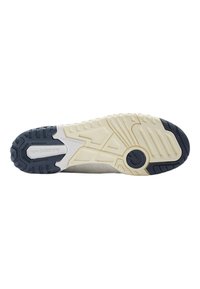 Beige athletic shoe sole with textured rubber grip, featuring white and dark blue accents, and a lightweight design with visible tread patterns.