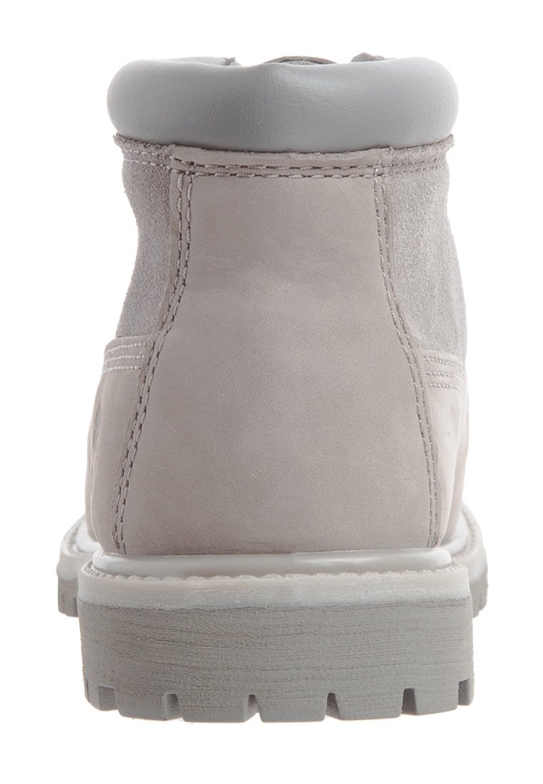 Botte en suède gris clair avec un col rembourré gris, semelle blanche et couture visible sur les côtés. Design texturé et durable.