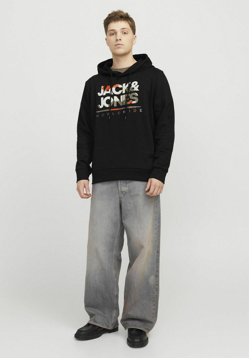 Felpa nera con stampa grafica dai colori chiari e la scritta "JACK & JONES WORLDWIDE." Jeans grigi chiari con vestibilità comoda e scarpe nere.