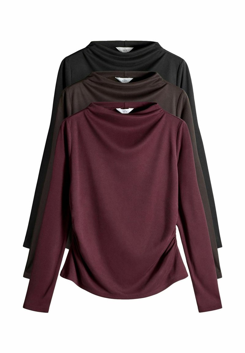 Tričko s dlhým rukávom zobrazené v stohovanej polohe: bordová vpredu, tmavohnedá a čierna. Mäkký materiál s prehnutým dizajnom a voľným strihom.