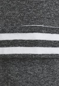 Grauer Stoff mit einem strukturierten Muster, der horizontalen weißen Streifen entlang der unteren Kante. Das Material wirkt weich und dehnbar.