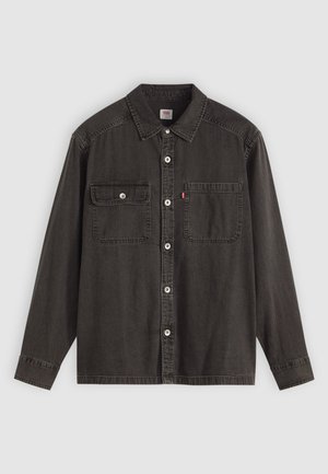 Sort denimskjorte med spidse kraver, to brystlommer med knapper og sølvknapper ned ad fronten. Lange ærmer med knapmanchetter.