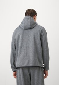 Sweat-shirt à capuche gris en tissu texturé, coupe décontractée, et grande capuche. Comprend des poignets et un ourlet côtelés.