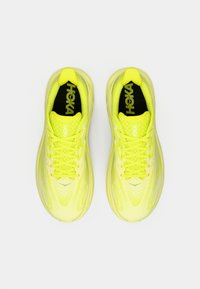 Limonengrüne Sportschuhe mit einem Mesh-Obermaterial, runden Schnürsenkeln und gepolsterter Sohle. Sie verfügen über ein Logo auf der Zunge und ein gemustertes Design an den Seiten.