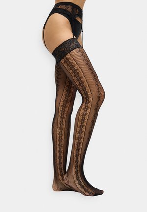 Een vrouw in zwarte kanten thigh-high kousen met een jarretelgordel en bijpassend zwart ondergoed, afgebeeld vanaf halverwege de bovenbenen naar beneden.