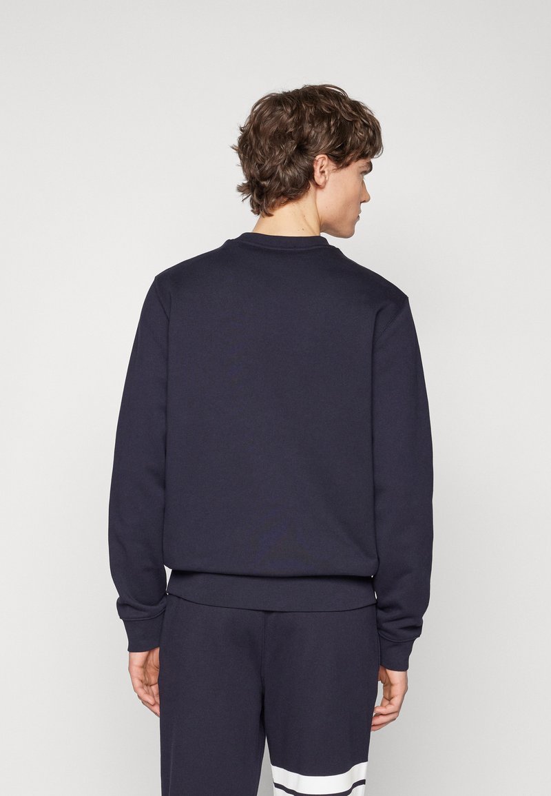 Sudadera de cuello redondo azul marino con puños y dobladillo acanalados, hecha de una suave mezcla de algodón, presenta un diseño minimalista sin logotipos visibles.