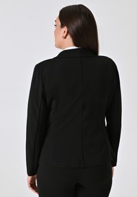 Zwarte getailleerde blazer met lange mouwen, een geknipte kraag en een gladde textuur. Bevat een centrale naad aan de achterkant voor een getailleerd silhouet.