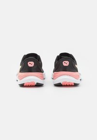 Zapatillas deportivas negras con acentos en rosa y suelas blancas. Presenta una parte superior de malla transpirable, un collar acolchado y una suela de goma texturizada.
