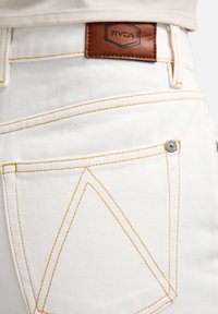 Λευκά τζιν από τζιν ύφασμα με αντίθετη κίτρινη ραφή, καφέ δερμάτινη ετικέτα RVCA στη μέση και ασημένια λεπτομέρεια κουμπιού στην τσέπη.