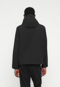 Black hooded jacket with a smooth texture and relaxed fit. Features long sleeves and a simple, minimalist design without visible hardware.