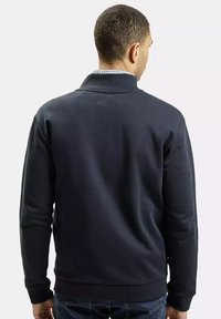 Granatowy sweter z wysokim kołnierzem, ściągaczami przy mankietach i u dołu. Gładka tekstura materiału z delikatnym detalem wzorniczym przy dekolcie.