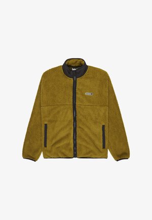 Villa-paita oliivinvihreänä, mustalla vetoketjulla ja kauluksella. Varustettu vetoketjulla olevalla edessä ja sivutaskuilla, joissa on tekstuuri.