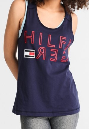 Canottiera blu navy con il testo rosso "HILFIGER", un piccolo logo e una vestibilità rilassata. Il tessuto sembra liscio con un taglio classico e senza ulteriori fantasie.