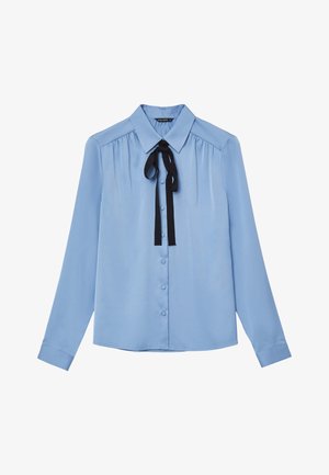 Blouse bleu clair à manches longues, fermeture à boutons, col classique et un nœud en ruban noir au cou. Texture lisse, semblable à du satin.