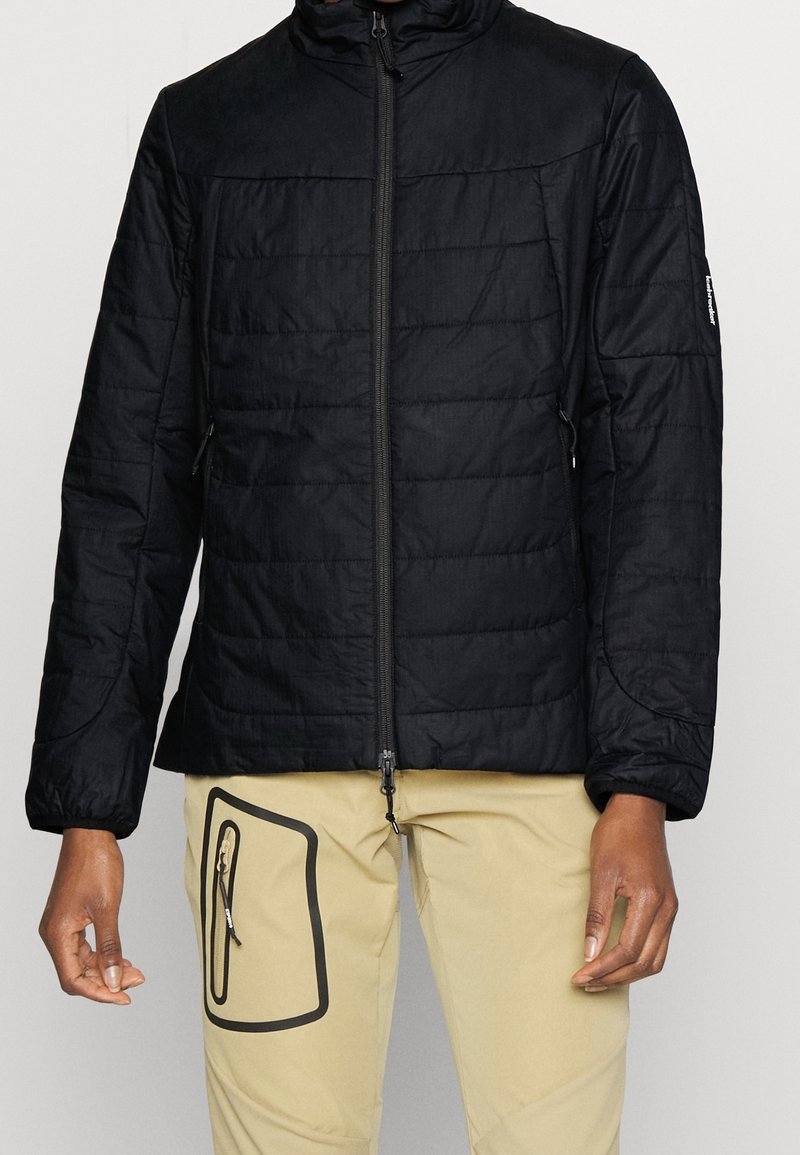 Černá prošívaná bunda s vysokým límcem a zipovým zapínáním. Má dlouhé rukávy a postranní kapsy; vyrobeno z lehkého, strukturovaného materiálu.