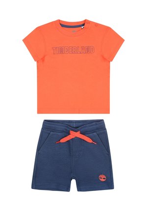 Oranje t-shirt met korte mouwen met de tekst "TIMBERLAND"; marineblauwe shorts met elastische tailleband en oranje trekkoord; beide gemaakt van katoen.