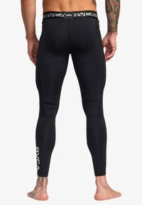 Sorte træningsleggings med et tætsiddende design, der har en logo-linning og hvid branding på underbenet. Glat, strækbart materiale.
