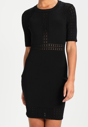 Schwarzes knielanges Kleid mit kurzen Ärmeln und perforierten Strickdetails an Ärmeln, Taille, Brust und Saum.