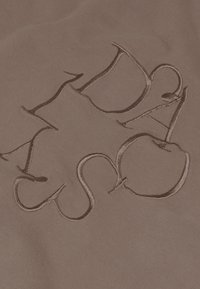 Un tissu marron présentant un design de logo en relief dans une teinte contrastante. Le tissu a une texture lisse, offrant une apparence douce.