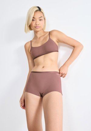 Bruine naadloze bralette en bijpassende shortset, gemaakt van gladde stof met een minimalistisch ontwerp en contrasterende afwerking aan de randen.