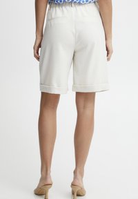 Shorts color crema con orlo arrotolato, realizzati in tessuto leggero, dotati di tasche posteriori e vita elastica, pensati per un abbigliamento casual.