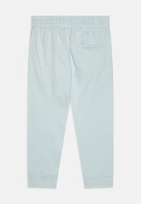 Pantalones de chándal azul claro con cintura elástica, pernera ajustada y un único bolsillo en la parte trasera; hechos de un tejido suave con una textura lisa.
