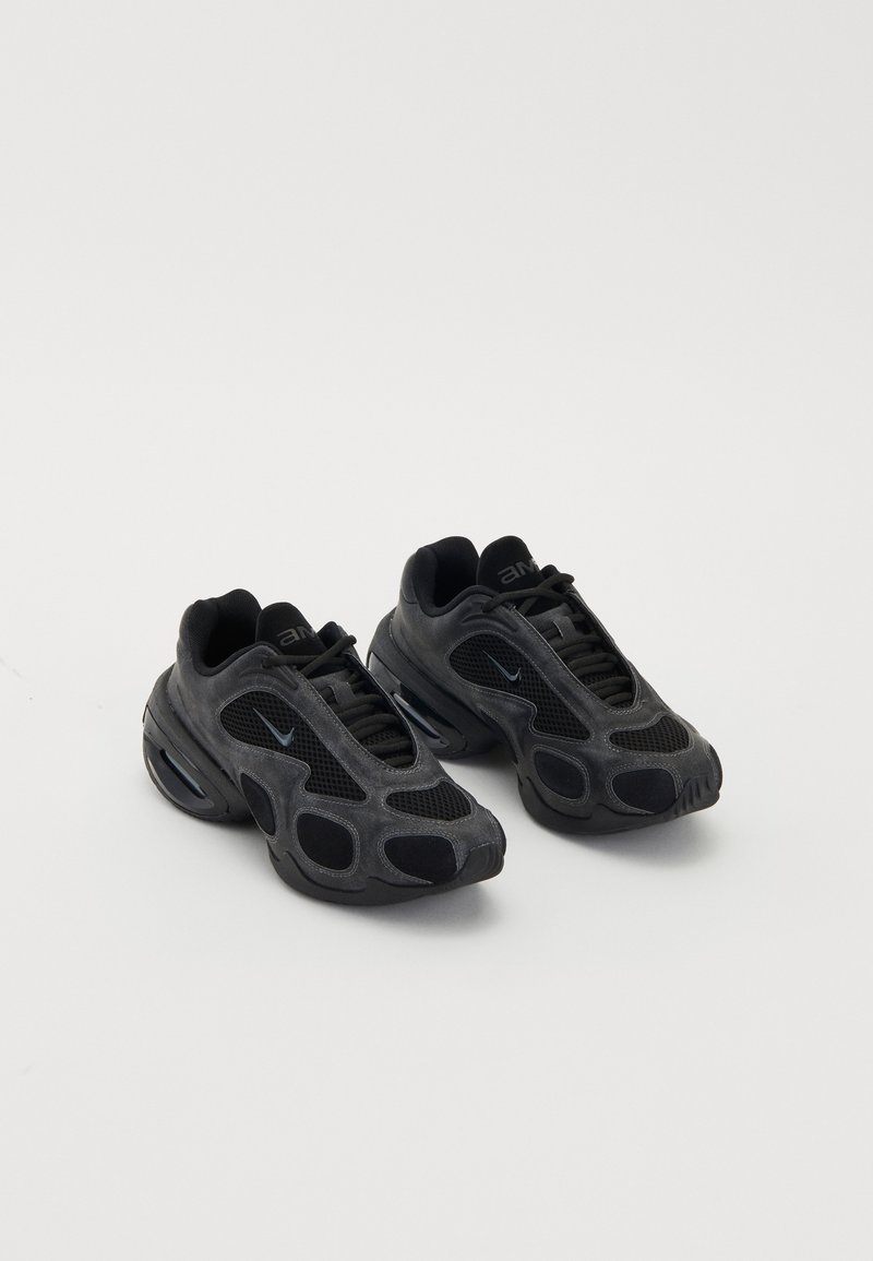 Baskets Nike noires avec des panneaux en maille et en daim, des découpes uniques et des colliers rembourrés. Des accents brillants sur les côtés mettent en valeur un design moderne.