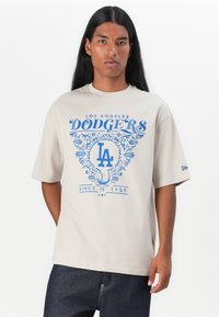 Lys beige kortærmet t-shirt med blåt Los Angeles Dodgers grafik og tekst, med en afslappet pasform og blød bomuldsstruktur.
